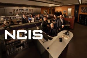 NCIS“-Promo-Bild: Das Ermittlerteam in einem Büro mit Schreibtischen und Computern. Im Fokus stehen die Charaktere der Serie, umgeben von Akten, Pinnwänden und einer professionellen Arbeitsumgebung. Der Schriftzug „NCIS“ ist prominent im Vordergrund platziert.