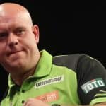 Michael van Gerwen, einer der bekanntesten Darts-Profis, im grünen Trikot bei einem Turnier, mit entschlossenem Blick und einer geballten Faust.