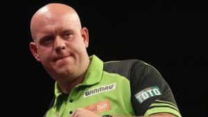 Michael van Gerwen, einer der bekanntesten Darts-Profis, im grünen Trikot bei einem Turnier, mit entschlossenem Blick und einer geballten Faust.