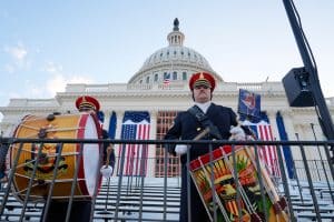 Zwei uniformierte Musiker der United States Army Band mit Trommel und Marschtrommel vor dem dekorierten Kapitol in Washington, das mit amerikanischen Flaggen geschmückt ist. Im Hintergrund ist die Kuppel des Kapitols zu sehen.