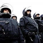 Eine Gruppe von Polizeibeamten in Einsatzuniformen und Helmen steht in einer Reihe. Sie tragen Schutzschilde und Ausrüstung für den Einsatz bei Großveranstaltungen oder Demonstrationen.