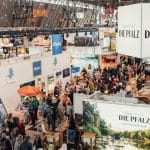 Eine belebte Messehalle der CMT in Stuttgart mit Ständen verschiedener Urlaubsregionen, darunter die Pfalz, das Allgäu und Bayern. Zahlreiche Besucher erkunden die Angebote der Aussteller.