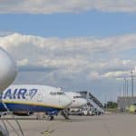 Zwei Ryanair-Flugzeuge stehen auf dem Rollfeld des Flughafens Karlsruhe/Baden-Baden vor einem Kontrollturm, bei klarem Himmel mit einigen Wolken. Im Hintergrund sind Flughafeninfrastruktur und Bäume zu sehen.