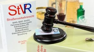 Symbolbild zum Thema Straßenverkehrsrecht und Alkoholkonsum: Ein Gesetzesbuch zum Straßenverkehrsrecht, ein Richterhammer auf einem Führerschein sowie alkoholische Getränke im Hintergrund. Darstellung rechtlicher Konsequenzen bei Alkohol am Steuer.