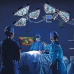 Ein hochmoderner Operationssaal mit chirurgischem Team in blauen OP-Kitteln und Mundschutz. Der Eingriff wird minimalinvasiv mit einem Endoskop durchgeführt, während ein Bildschirm hochauflösende Live-Bilder des Eingriffs zeigt. Die OP-Beleuchtung besteht aus LED-basierten Leuchten mit innovativem Design. Rechts im Bild ist modernste Medizintechnik mit vernetzten Geräten zu sehen.