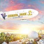 Illustration: Der Europa-Park Zeppelin mit dem Jubiläumslogo 2025 fliegt über den Freizeitpark, umgeben von einer malerischen Abendstimmung mit Achterbahnen und der markanten Kuppel im Hintergrund.
