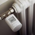 Ein weißer Heizkörper mit einem modernen, digitalen Thermostat, das auf 16,0 Grad Celsius eingestellt ist.