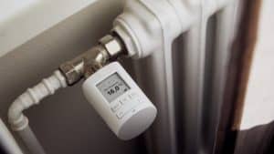 Ein weißer Heizkörper mit einem modernen, digitalen Thermostat, das auf 16,0 Grad Celsius eingestellt ist.