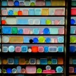 Ein Regal mit einer bunten Sammlung von Tupperware-Behältern in verschiedenen Formen und Farben, symmetrisch angeordnet und kunstvoll beleuchtet.