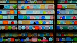 Ein Regal mit einer bunten Sammlung von Tupperware-Behältern in verschiedenen Formen und Farben, symmetrisch angeordnet und kunstvoll beleuchtet.