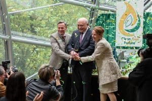 "Die Toten von Salzburg – Süßes Gift": Josef Wittmann (Johannes Zirner), Gustav Nussbaumer (Karl Fischer) und Susanne Zirner (Susanne Czepl) stehen zusammen auf einem Podest vor Journalisten (Komparsen). Sie haben ihre Hände in der Mitte aufeinander gelegt und es regnet Konfetti auf sie. Im Hintergrund hängt ein Plakat mit der Aufschrift "Clean Future".