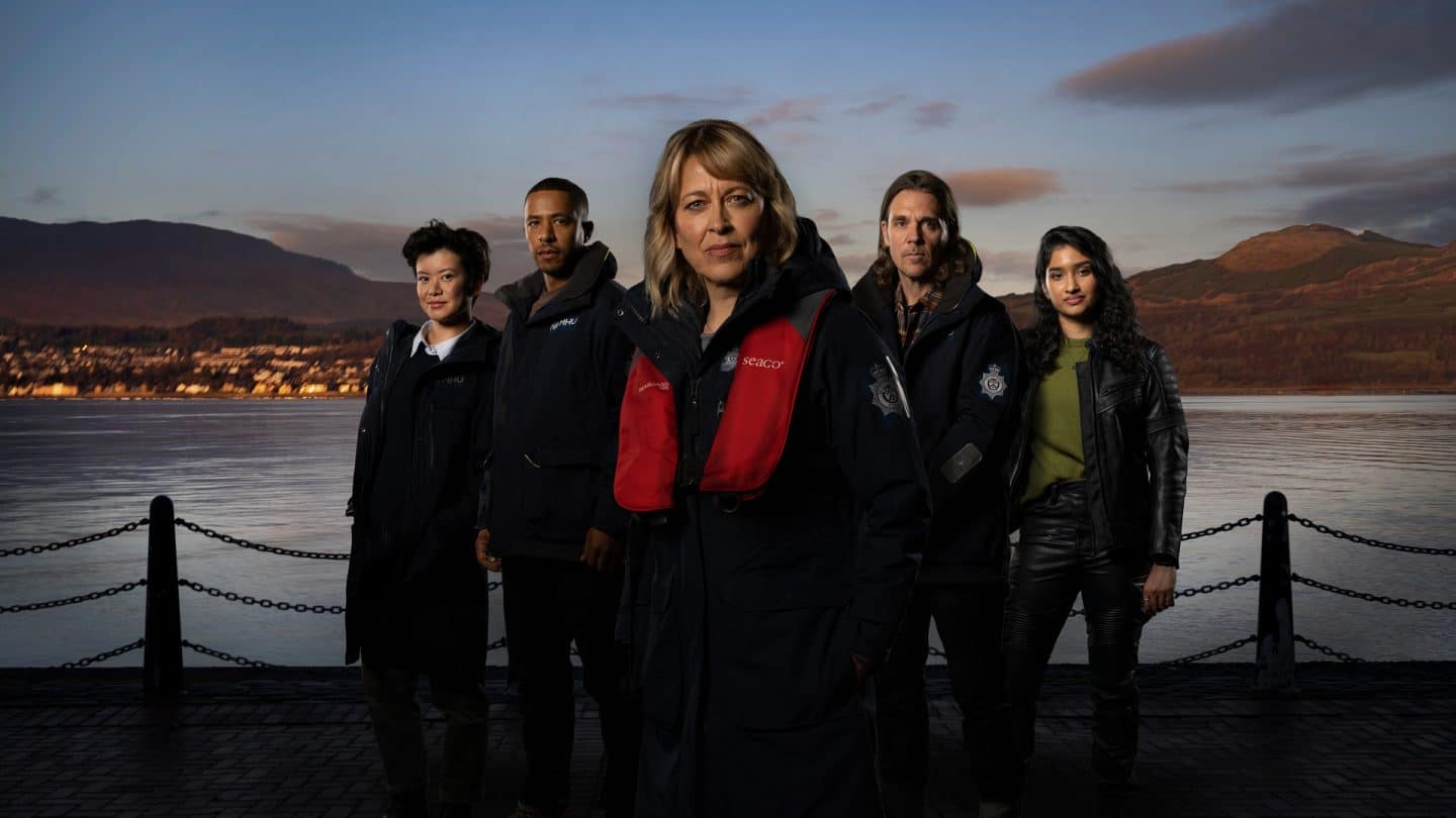"Annika – Mord an Schottlands Küste - Der Seehund": DC Blair Ferguson (Katie Leung), DS Tyrone Clarke (Ukweli Roach), DI Annika Strandhed (Nicola Walker), DS Michael McAndrews (Jamie Sives) und DC Harper Weston (Varada Sethu) stehen nebeneinander und blicken in die Kamera. Im Hintergrund ist ein Gewässer zu sehen.
