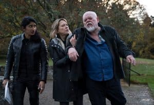 "Annika – Mord an Schottlands Küste - Wahre Werte": Harper (Varada Sethu), Annika (Nicola Walker) und Magnus (Sven Henriksen) gehen auf einem Weg im Naturresort. Annika stützt ihren betrunkenen Vater. Harper beobachtet die beiden.