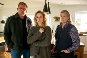 "Der Bergdoktor: Sternenkinder": In der Küche der Familie Weiss: Ängstlich hält Jana Weiss (Pia Barucki) ihre Strickjacke fest vor der Brust zusammen und wirkt abwesend. Neben ihr stehen Dr. Martin Gruber (Hans Sigl) und Ulla Hoppe (Birge Schade). Beide blicken ernst.