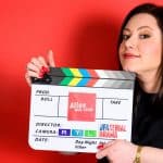 Julia Augustin hält eine Filmklappe in der Hand