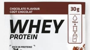 Eine Packung des Decathlon Whey Proteinpulvers mit Schokoladengeschmack (30 g). Die Verpackung ist überwiegend weiß mit braunen Akzenten und zeigt ein Abbild des Kakaopulvers. Auf der Vorderseite sind Informationen wie "21 g Whey-Protein pro 30 g", "Mit Stevia-Blattextrakt" und das Fairtrade-Logo zu sehen.