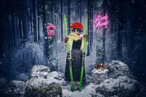 Die KI-generierte Markenbotschafterin „Schwarzwald Marie“ in einer winterlichen Schwarzwald-Szene: Sie trägt den traditionellen roten Bollenhut, eine Sonnenbrille, ein modernes Dirndl mit langem dunklen Rock sowie einen dicken Schal. In den Händen hält sie grüne Skier. Im Hintergrund sorgen eine pinke Kuckucksuhr an einem Baum sowie ein neonpinkes Schild mit der Aufschrift „Kuck Kuck“ für einen modernen Kontrast zur verschneiten Waldlandschaft.