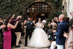 Das Brautpaar Nathalie Gaus und Cosimo Citiolo verlässt nach der Zeremonie strahlend die Hochzeitslocation, während Freunde und Familie sie mit Blütenblättern bejubeln.