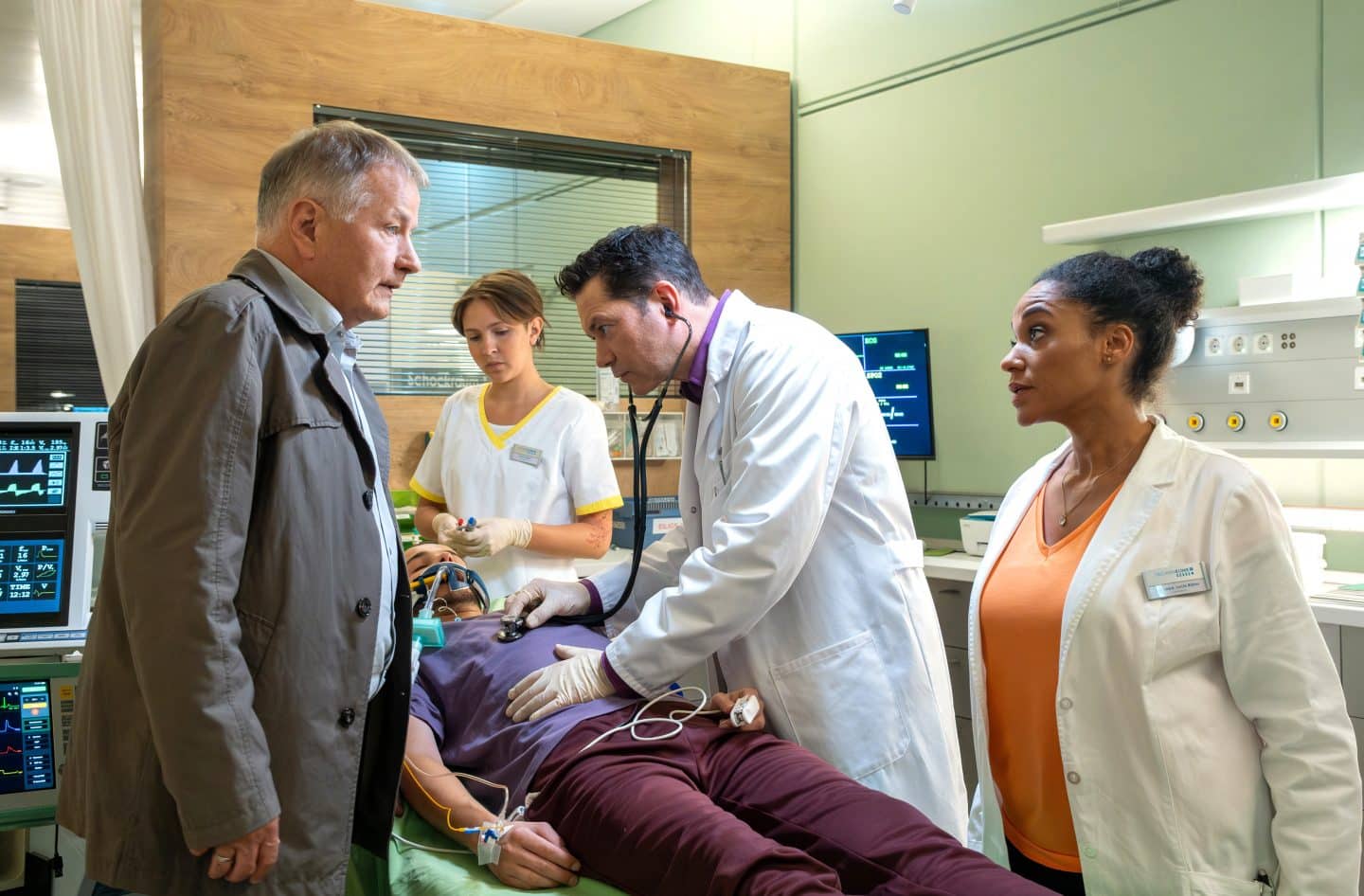 „In aller Freundschaft“: Zwei neue Folgen heute – Not-OP und dramatische Enthüllung! 1 Jonas Heilmann (Anthony Petrifke, liegend) ist zu Hause bewusstlos zusammengebrochen. Dr. Philipp Brentano (Thomas Koch, 2.v.re.) hat den Verdacht, dass es eine Blutung im Hirn sein könnte. Dr. Roland Heilmann (Thomas Rühmann, li.) will natürlich bei seinem Enkel bleiben. Doch die Leiterin der Notaufnahme Dr. Lucia Böhm (Vanessa Rottenburg, re.) macht ihm unmissverständlich klar, dass er in diesem Fall "nur" Angehöriger ist. Roland ist nun zum Warten verdammt.