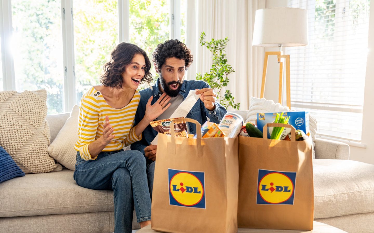 Ein Mann und eine Frau sitzen auf einem Sofa mit Einkaufstüten.