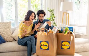 Ein Mann und eine Frau sitzen auf einem Sofa mit Einkaufstüten.