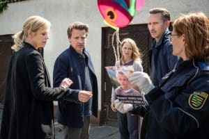 "SOKO Leipzig - Sunny": Vor dem Haus: Ina Zimmermann (Melanie Marschke), Moritz Brenner (Johannes Hendrik Langer) und eine Polizistin (Komparsin) sprechen mit Kai Marlow (Max von Pufendorf) und seiner Frau Marlene Marlow (Theresa Scholze). Alle schauen sehr angespannt auf ein Papier, dass die Polizistin in Händen hält.