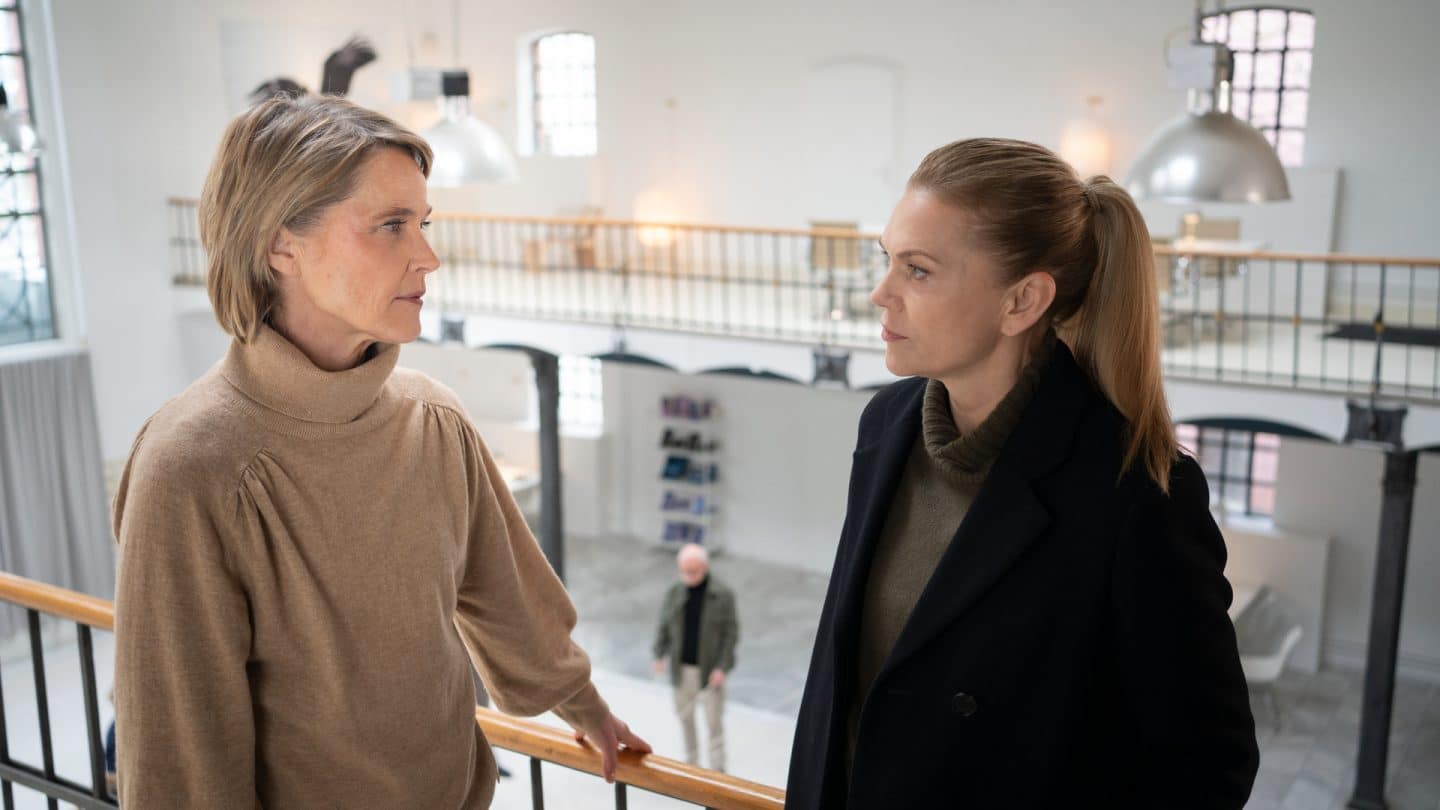 "Helen Dorn - Schwarzes Herz": Helen Dorn (Anna Loos) und Charlotte Falkner (Karoline Eichhorn) stehen zusammen in einem Saal auf der Galerie am Geländer und unterhalten sich.
