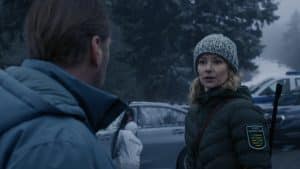 "Erzgebirgskrimi - Wintermord": Försterin Saskia Bergelt (Teresa Weißbach) blickt besorgt zu Hauptkommissar Robert Winkler (Kai Scheve). Im Hintergrund stehen mehrere Autos und jemand von der Spurensicherung arbeitet an dem Auto.