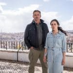 "Flucht aus Lissabon": Sophia (Hana Sofia Lopes) steht zusammen mit Tom Fährmann (Hans Sigl) auf einer bekannten Aussichtsplattform in Lissabon. Mit ernster und fragender Miene schauen beide in Richtung Kamera. Tom Fährmann hat die Hände in den Hosentaschen. Im Hintergrund sieht man die Häuser der Stadt von oben.