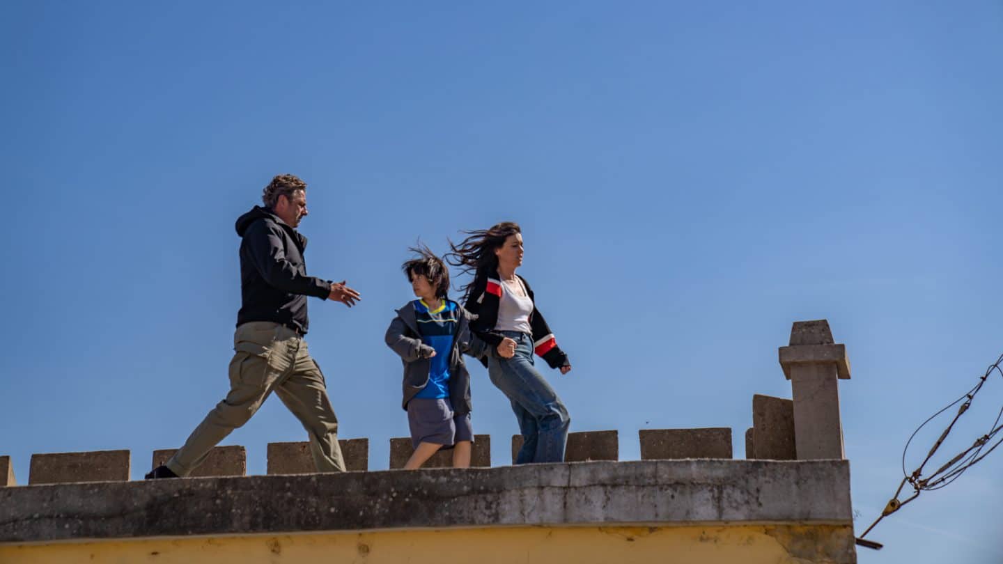 "Flucht aus Lissabon": Tom (Hans Sigl), Noa (Santiago André) und Sophia (Hana Sofia Lopes) rennen über ein Hausdach. Dabei hält Sofia die Hand von Noa, der sich besorgt nach Tom umblickt.
