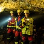 "Marie fängt Feuer - Verschüttet": Marie (Christine Eixenberger) steht mit einer Taschenlampe in der Hand in der Höhle und leuchtet tiefer in die Höhle hinein. Peter (Stephan Luca) und Flori (Xiduo Zhao), stehen hinter ihr und leuchten mit ihren Taschenlampen in die gleiche Richtung.