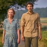 "Zimmer im Grünen - Herzenswege": Frieda (Therese Hämer) und Heinrich (Tobias van Dieken) laufen entspannt auf einem von Wiesen umgebenen Weg, im Hintergrund liegt der Waldrand.
