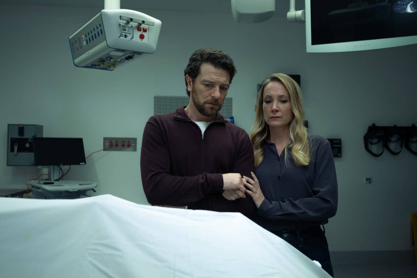 Mord, Macht und Intrigen: „North Shore – Tod in Sydney“ feiert Free-TV-Premiere! Krimi-Highlight oder Enttäuschung? 1 "North Shore – Tod in Sydney - Drummond Down Under": Abigail Crawford (Joanne Froggatt) und ihr Mann Simon Chalcott (Dan Spielman) stehen nebeneinander in einem Raum in der Gerichtsmedizin. Vor ihnen auf dem Tisch liegt eine Leiche unter einem weißen Tuch. Abigail hält Simons Hand.