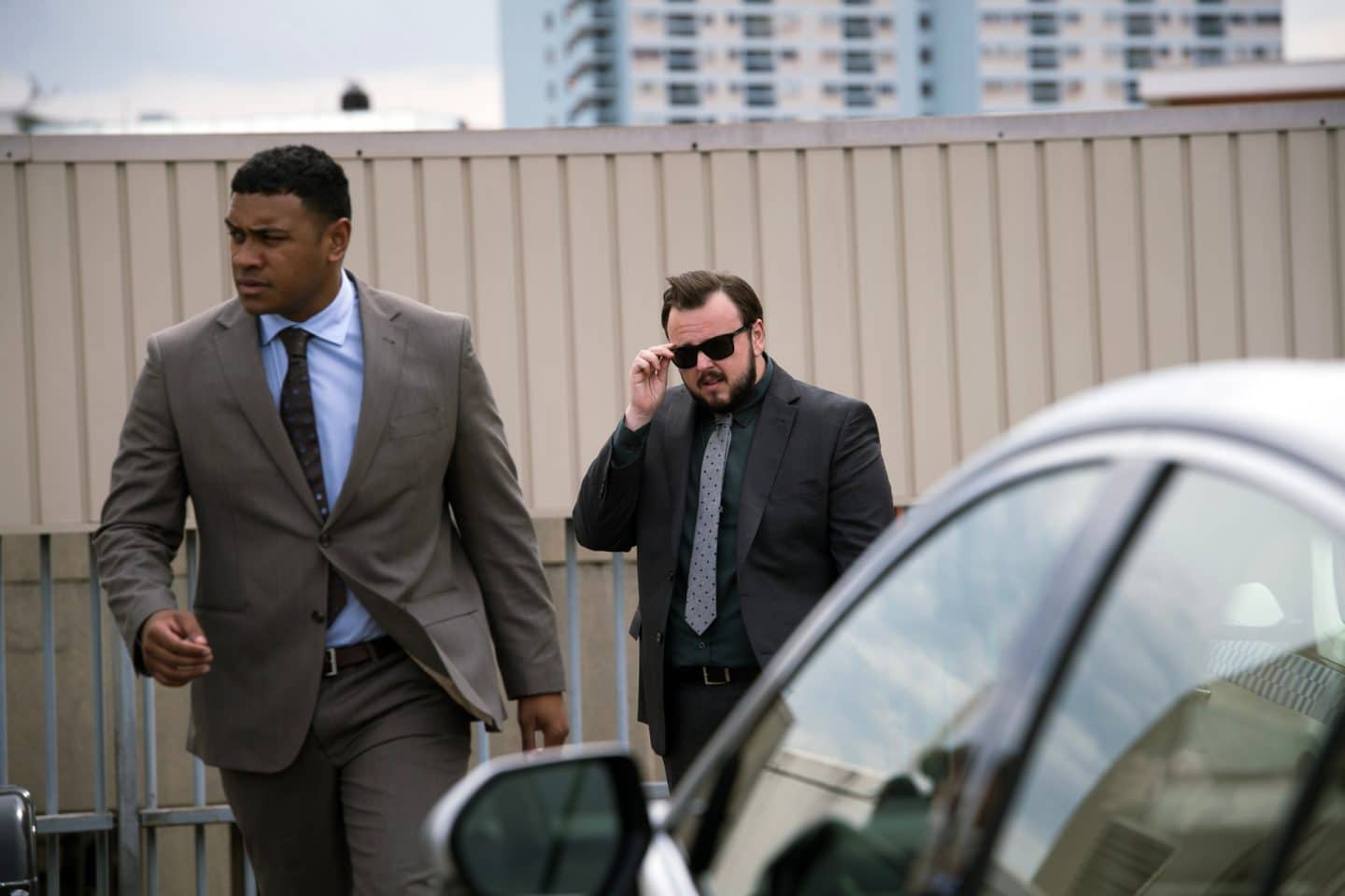 Mord, Macht und Intrigen: „North Shore – Tod in Sydney“ feiert Free-TV-Premiere! Krimi-Highlight oder Enttäuschung? 3 "North Shore – Tod in Sydney - Stanleygate": DC Paea Leniu (Chris Alosio) geht an einem geparkten Auto vorbei. DS Max Drummond (John Bradley) folgt ihm. Max fasst mit der rechten Hand an einen Bügel seiner Sonnenbrille.