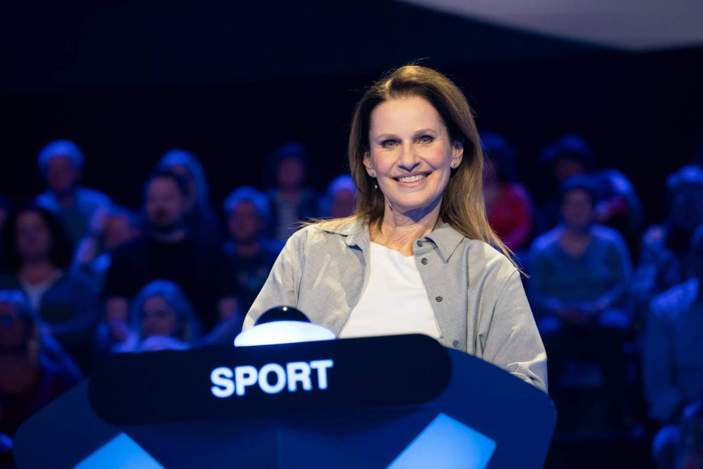 "Der Quiz-Champion - Das Bundesländer-Special": Katrin Müller-Hohenstein sitzt am Ratepult im Studio und lächelt in die Kamera, im Hintergrund sitzt das Publikum.
