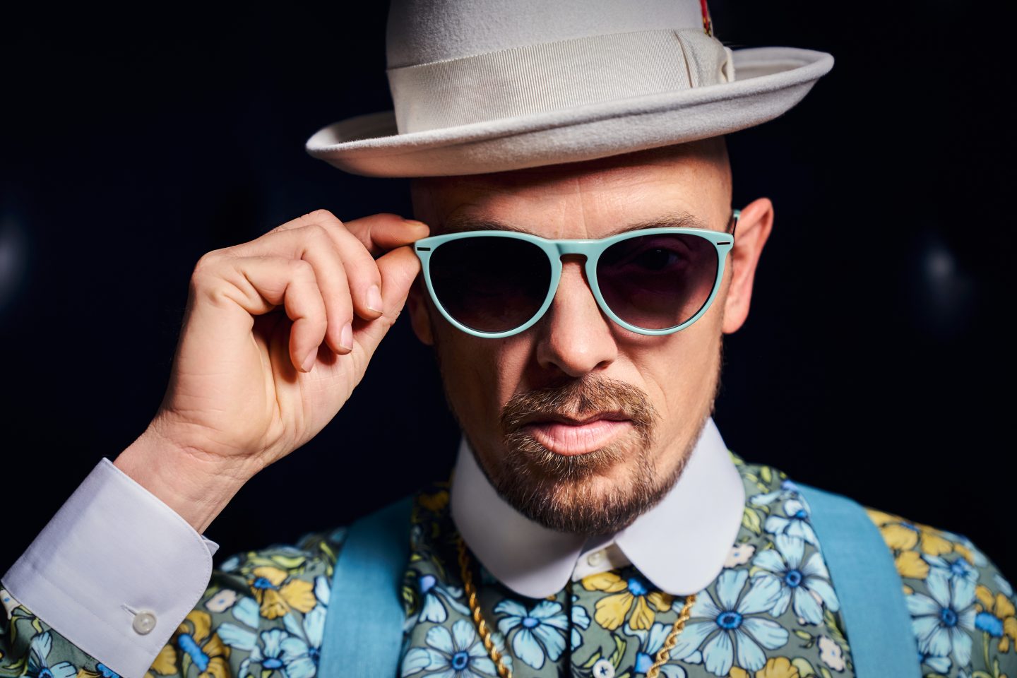 Erster Trailer zu "Grand Prix of Europe" – Europa-Park bringt Ed & Edda ins Kino – Jan Delay als Enzo! 1 Jan Delay mit weißem Hut und mintgrüner Sonnenbrille. Der Musiker trägt ein buntes, florales Hemd mit blauen Hosenträgern und schaut ernst in die Kamera