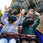 Zwei begeisterte Kinder mit VR-Brillen erleben eine Achterbahnfahrt im Europa-Park. Mit erhobenen Armen genießen sie das virtuelle Coastiality-Erlebnis, während die Schienen und die Felslandschaft im Hintergrund die immersive Kombination aus realer und digitaler Welt unterstreichen.