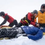 "Die Bergretter: Eiskalte Wahrheit (2)": Simon (Ferdinand Seebacher), Katharina (Luise Bähr) und Markus (Sebastian Ströbel) verarzten den verletzten Daniel Faltermayer (Julian Felix), der im Schnee liegt.