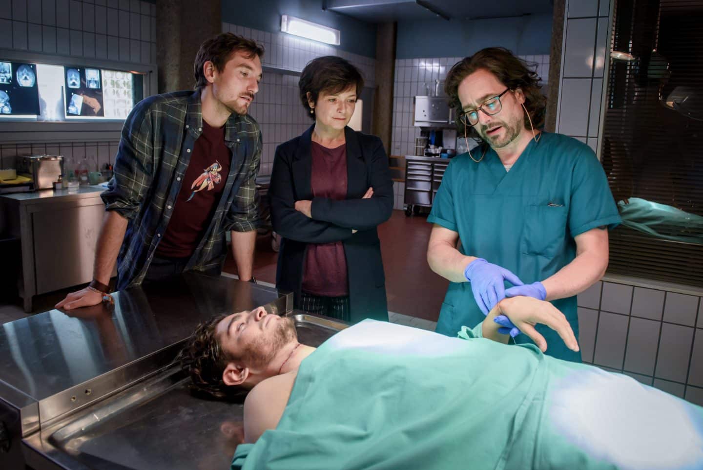 "SOKO Linz - Wir kennen dich": Vor dem Obduktionstisch auf dem die Leiche liegt, stehen Ben Halberg (Daniel Gawlowski), Johanna "Joe" Haizinger (Katharina Stemberger) und Dr. Richard "Richie" Vitek (Alexander Pschill) vor der Leiche und besprechen die gefundenen Indizien. Dabei erläutert Dr. Richie Vitek einen wichtigen Hinweis auf der Hand des Opfers.