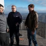 "SOKO Stuttgart – Tod im Turm": IT-Spezialist Rico Sander (Benjamin Strecker) steht mit geballten Fäusten und dem Rücken an den Turm gepresst auf der Aussichtsplattform des Stuttgarter Fernsehturms. Neben ihm befindet sich der Aufzugsführer Jürgen Spengler (Oliver Breite) und Jo Stoll (Peter Ketnath), der sich sichtlich über die Höhenangst seines Kollegen amüsiert. Im Hintergrund erstreckt sich ein Landschaftspanorama.