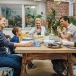 "Das gläserne Kind": Auf einer Terrasse sitzen Helen Schuchardt (Hanna Plaß),Luke (Lennox Louis Steigerschmid), Anne Schuchardt (Katharina Böhm), Franz (Philip Dechamps) und Daniel (David Zimmerschied) gemeinsam an einem gedeckten Holztisch. Alle unterhalten sich mit einem Lächeln im Gesicht.