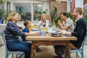 "Das gläserne Kind": Auf einer Terrasse sitzen Helen Schuchardt (Hanna Plaß),Luke (Lennox Louis Steigerschmid), Anne Schuchardt (Katharina Böhm), Franz (Philip Dechamps) und Daniel (David Zimmerschied) gemeinsam an einem gedeckten Holztisch. Alle unterhalten sich mit einem Lächeln im Gesicht.