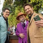 "Bares für Rares - Deutschlands größte Trödelshow": Colmar Schulte-Goltz, Horst Lichter und August Wittgenstein stehen dicht nebeneinander am Expertisenpult und lachen in Wittgensteins Handy, das dieser zum Selfie ausgestreckt in der linken Hand hält. Im Hintergrund steht das Publikum vor Bäumen.