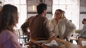 Nathalie, Matteo und Valea stehen gemeinsam in einem Café und führen ein angespanntes Gespräch, während Nathalie zwischen den beiden Männern positioniert ist.