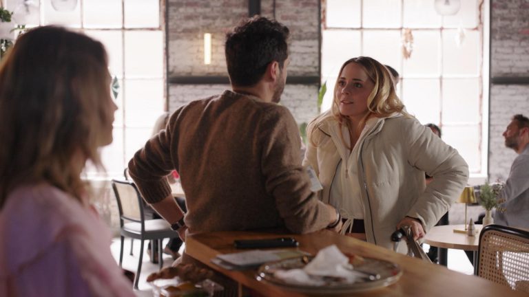 Nathalie, Matteo und Valea stehen gemeinsam in einem Café und führen ein angespanntes Gespräch, während Nathalie zwischen den beiden Männern positioniert ist.