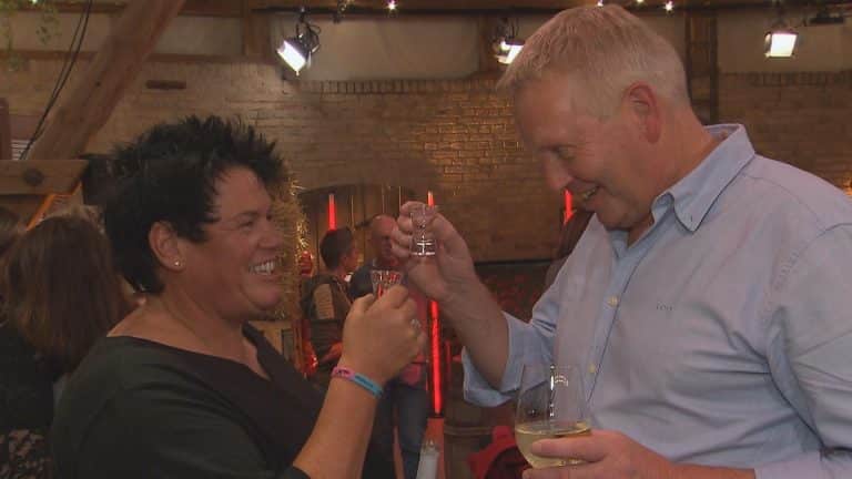 Simone und Jörg stoßen beim Finale von „Bauer sucht Frau“ lachend mit einem Schnapsglas und einem Weinglas an.