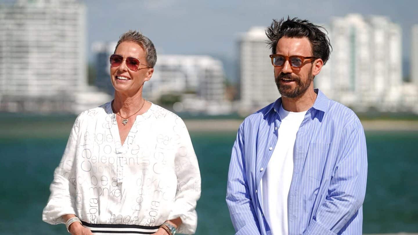 Sonja Zietlow und Jan Köppen  stehen am Wasser, beide tragen Sonnenbrillen und lächeln.