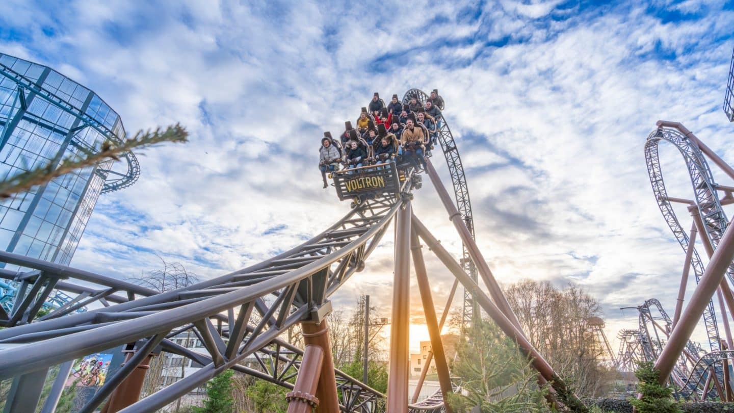 Fahrgäste in einem Wagen der Achterbahn Voltron im Europa-Park während einer Fahrt über eine steile Schienenkonstruktion bei Tageslicht.