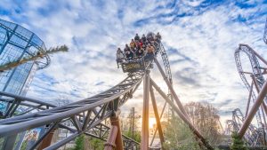 Fahrgäste in einem Wagen der Achterbahn Voltron im Europa-Park während einer Fahrt über eine steile Schienenkonstruktion bei Tageslicht.
