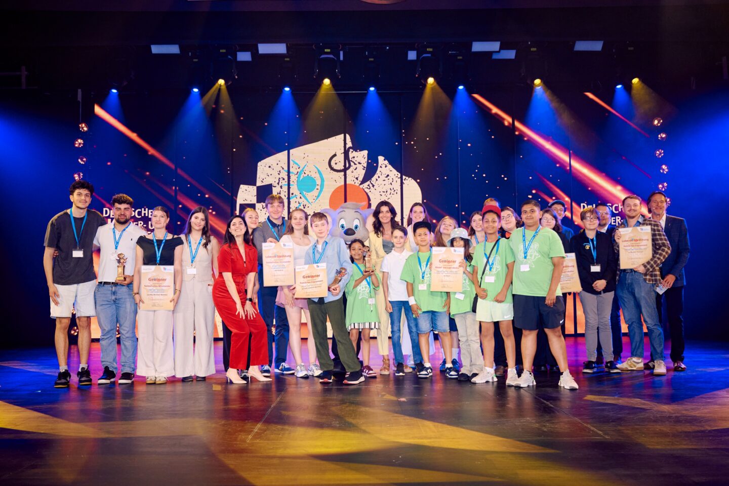 Gruppe von Kindern und Jugendlichen auf einer Bühne mit Urkunden und Medaillen.